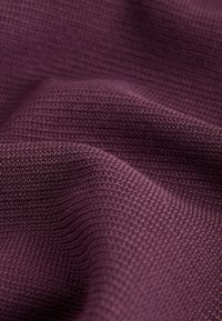 Strukturiertes lila Strickgewebe mit einem Waffelmuster, das Weichheit und Elastizität zeigt, mit einer glatten Oberfläche und dezentem Glanz.