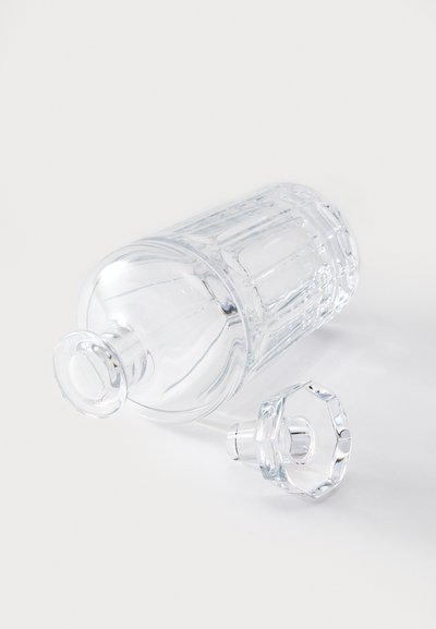 Klarer Glasbehälter mit zylindrischer Form, versehen mit vertikalen Rillen und einem sechseckigen Deckel. Glatte Textur mit glänzendem Finish.