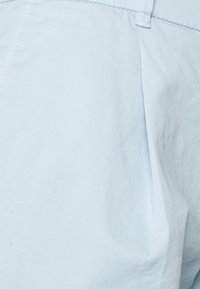 Light blue cotton shorts featuring a soft texture, pleated design, and practical stitching details. Ideal for casual wear.