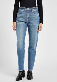 High-waisted blauwe denim jeans met een rechte snit, lichte vervaging en een klassiek vijfzakken ontwerp. Gecombineerd met zwarte enkellaarzen.