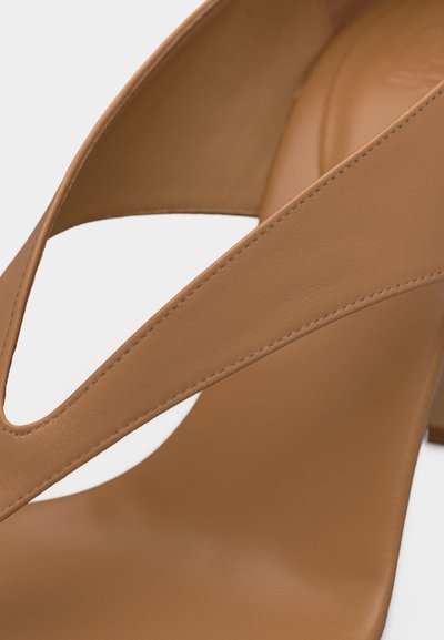 Κοντινό πλάνο ταμπά δερμάτινου ψηλοτάκουνου παπουτσιού με φαρδιές, λοξές λουρίδες και λεία ραφικά στοιχεία.