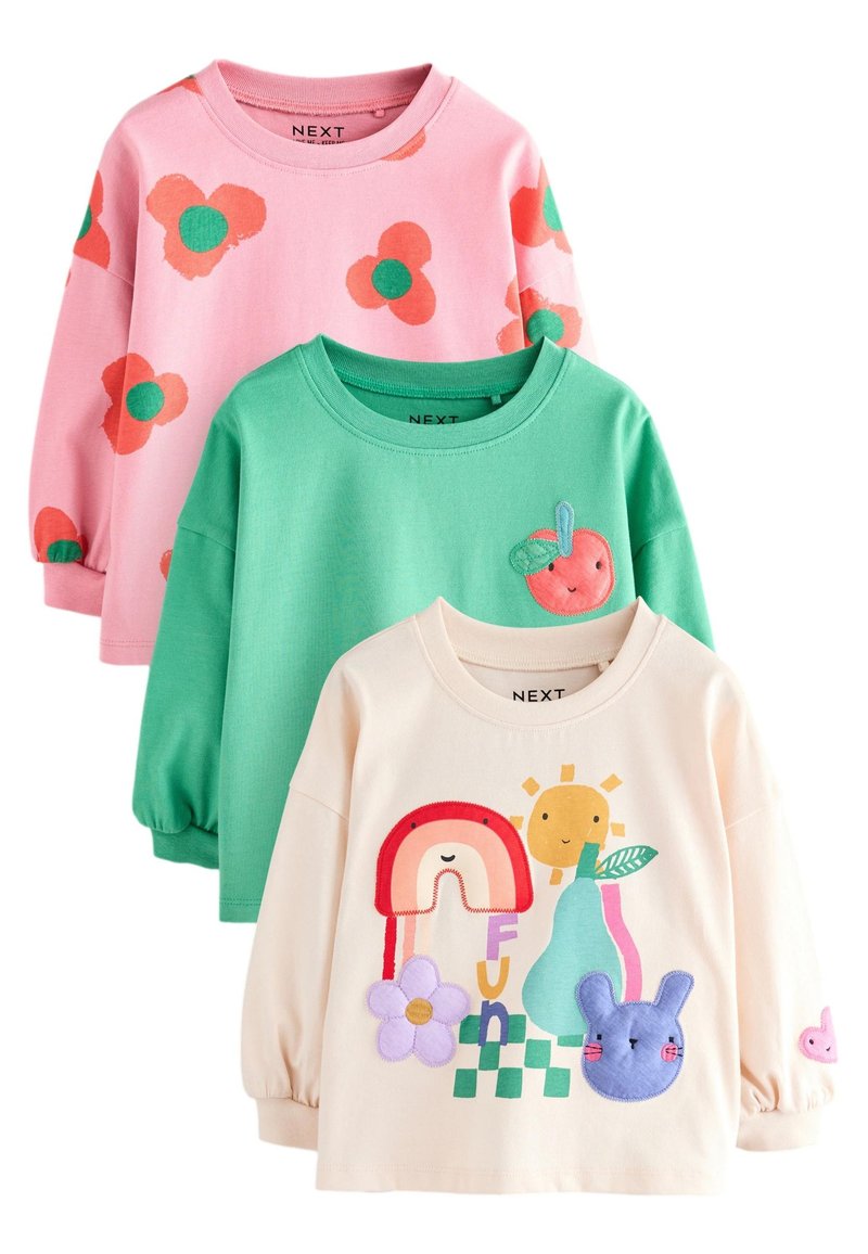Tres camisas de manga larga: rosa con estampado floral rojo y verde, verde con una manzana bordada y crema con diseños coloridos de animales y flores.