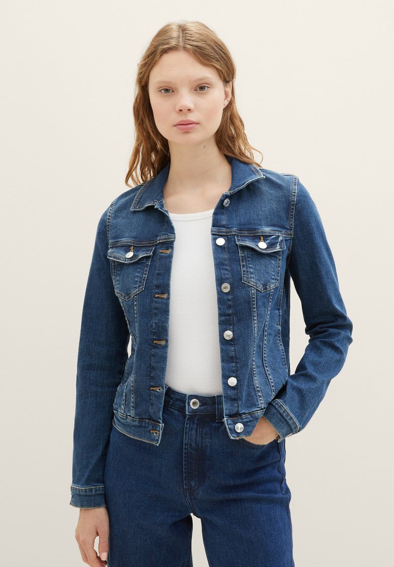 Denim jacket in dark blue, featuring a button-front closure, two chest pockets, and a structured design with a classic collar.