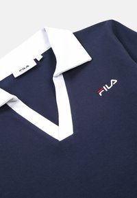 Mörkblå pikétröja med vit krage, med V-halsdesign och broderad Fila-logotyp i röd, vit och blå. Mjuk bomullstextur.
