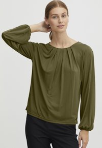 Olivenfarget bluse med lange, rynkede ermer og rund hals med myk drapering. Laget av lett, strukturert stoff.
