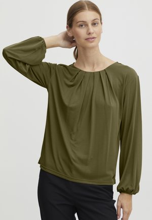 Blouse vert olive avec des manches longues froncées et un col rond avec un drapé doux. Fabriquée en tissu léger et texturé.