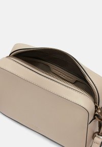 Beige Lederhandtasche mit Reißverschluss, präsentiert eine glatte Textur und genähte Akzente und verfügt über ein Innenfach für Karten.