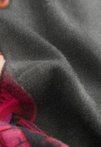 Tessuto nero testurizzato, caratterizzato da una superficie liscia con fibre sottili. Parti di un grafico rosso sono visibili sul bordo inferiore.