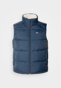 Marinblå puffer-väst med hög krage, framzipper och horisontell sömnad. Fodrad på insidan med ljusfärgad fleece. Litet logotyp på bröstet.