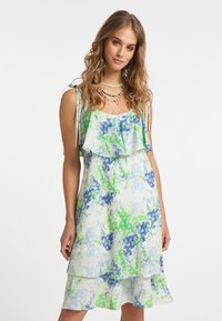 Ärmelloses Kleid mit einem gestuften Design, das ein blaues und grünes abstraktes Blumenmuster aufweist und aus leichtem Stoff gefertigt ist.