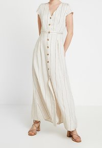 Maxi dress in light beige with vertical stripes. Features short sleeves, a V-neck, a button front, a waist tie, and wooden buttons.
