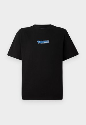 Svart kortärmad T-shirt med blå och vit "Tommy Jeans" logotyp centrerad på bröstet, visad mot en enkel ljus bakgrund.