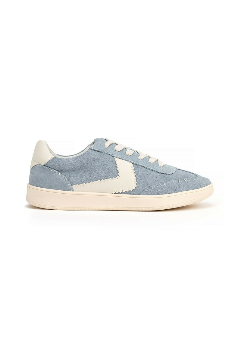 Sneaker in suede azzurro chiaro con suola in gomma crema, lacci crema e un accento bianco scallopato sul lato. Design atletico classico.