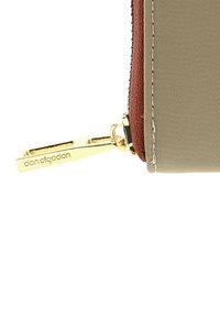 Cartera beige con acabado texturizado, acento marrón contrastante y tirador de cremallera en dorado con el nombre de la marca grabado.