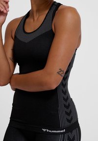 Zwart sporttanktop met een mesh halslijn, gevlekte patronen en een aansluitend ontwerp. Bevat een logo aan de zoom en gestructureerde zijdetails.