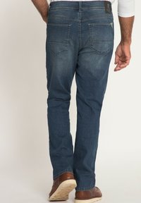 Jeans in denim blu scuro con taglio dritto, dotati di tasche posteriori, leggera scoloritura e una patch in pelle del marchio in vita.