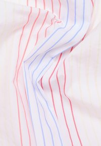 Tejido ligero con rayas verticales rojas, azules y amarillas sobre un fondo blanco. Textura suave con caída fluida y colores vibrantes.