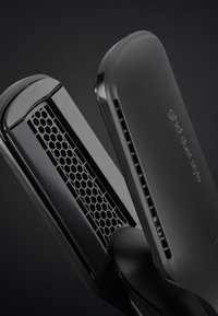 Lisseur à cheveux noir avec plaques en céramique à motif nid d'abeille et fentes de ventilation, étiqueté "ghd duet style" sur un côté.