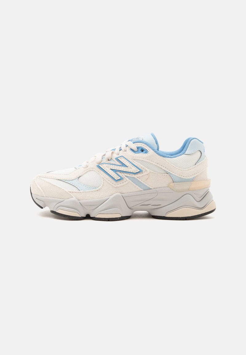 Λευκό και ανοιχτό μπλε sneaker New Balance με επάνω μέρος από δίχτυ και σουέντ, παχιά σόλα και κορδόνια, απεικονίζεται από το πλάι σε απλό φόντο.