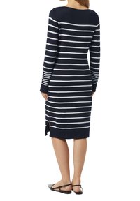 Marineblaues gestreiftes Kleid mit langen Ärmeln, das horizontale weiße Streifen, seitliche Schlitze und eine gerippte Textur an den Bündchen und dem Saum aufweist.