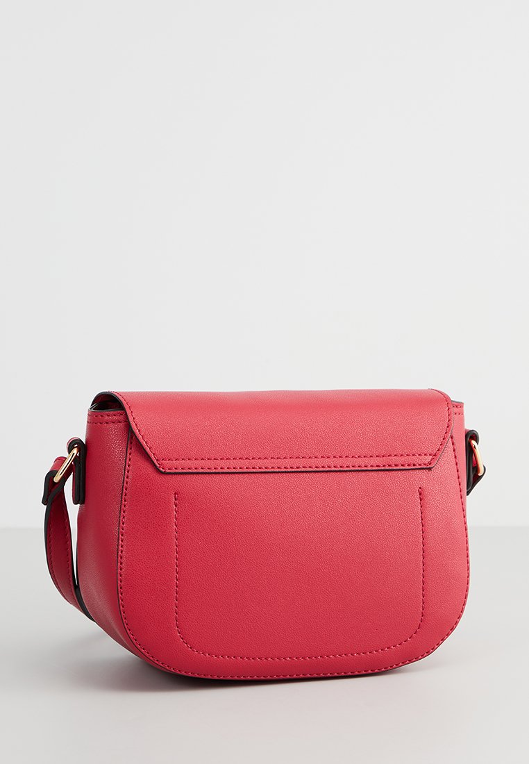 Sac bandoulière en simili cuir rouge avec fermeture à rabat, de forme arrondie et avec une seule sangle ajustable. Présente un design minimaliste et des coutures discrètes.