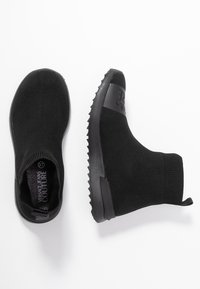 Black ankle boots with a knitted upper, ribbed cuff, and textured rubber sole. Features a logo band on the outer side.