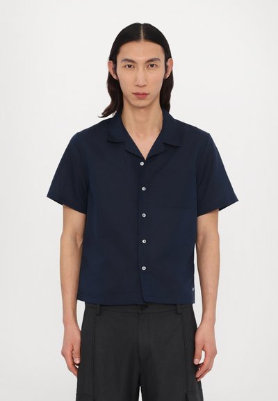 Short-sleeve navy button-up shirt with a pocket, lightweight fabric, and a relaxed fit. Features a camp collar and subtle button accents.