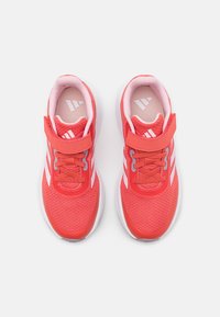 Zapatillas deportivas rojas con parte superior de malla, acentos blancos y correa ajustable. Presenta un tejido texturizado y una plantilla acolchada para mayor comodidad.
