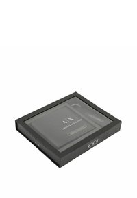 Black gift box featuring a clear lid, containing a black wallet and keychain with silver accents and the "A|X Armani Exchange" logo.