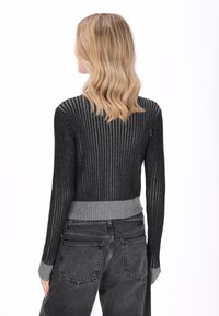 Sötétszürke bordás pulóver testhez simuló kialakítással, világosabb szürke alsó szegéllyel és mandzsettával. Könnyű anyag, függőleges textúrával.