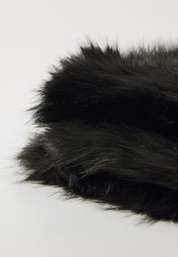 Black faux fur fabric with long, soft fibers and a dense texture, showcasing a subtle sheen and natural movement in the strands.