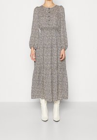 Robe à manches longues, imprimée de fleurs, avec un col rond, des détails de boutons et une taille froncée, associée à des bottes blanches au-dessus du genou.