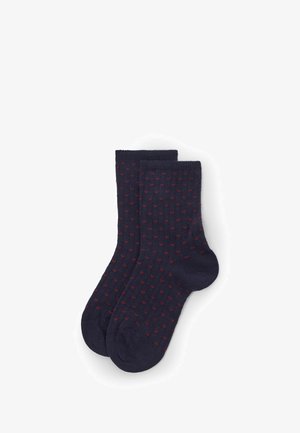 Marineblaue Socken aus Strickstoff, mit einem Muster aus kleinen roten Punkten. Knöchelhohes Design mit gerippten Bündchen und verstärkten Zehen.