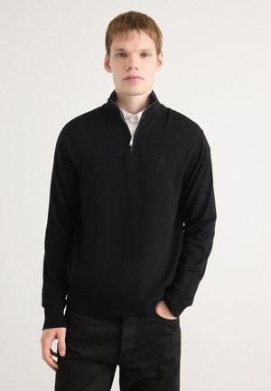 Zwarte pullover trui met een hoge hals en een rits, gemaakt van zacht materiaal. Beschikt over lange mouwen en een subtiele logo op de borst.