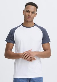 White short-sleeve T-shirt with navy raglan sleeves and crew neckline. Smooth fabric with contrasting color detail on shoulders.