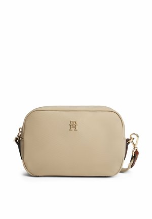 Beige leather crossbody bag with gold hardware, rounded shape, embossed logo on the front, and an adjustable strap with accent details.