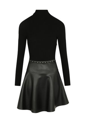 Top a collo alto nero a costine abbinato a una gonna a ruota in pelle nera con una vita borchiata e una texture liscia e lucida.