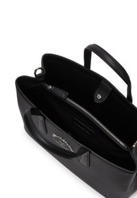 Black leather handbag, textured exterior, neat design. Open interior with a zippered pocket and logo tag, short handles for carrying.
