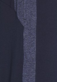 Marinblå t-shirt med ett vertikalt panel i heathergrått, bomullsmaterial, korta ärmar och en avslappnad passform. Texturerad tyg kontrasterar med slätt.