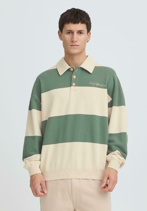 Grün-weiß gestreiftes Poloshirt mit Kragen, drei Holzknöpfen und gesticktem Text. Weiche Textur und lockere Passform.