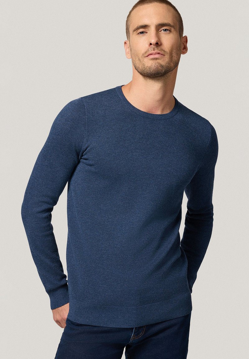 Dzianinowy sweter w kolorze granatowym z okrągłym dekoltem, długimi rękawami i ściągaczami. Teksturowana tkanina prezentuje subtelny wzór. Minimalistyczny design.