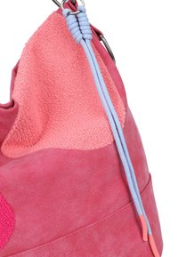 Borsa in suede rosa e terry con cordini intrecciati blu chiaro e dettagli in anello di metallo su uno sfondo bianco.