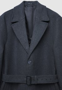Cappotto in misto lana grigio carbone con colletto a revers, chiusura con un solo bottone e vita con cintura. Finitura testurizzata con fodera liscia.