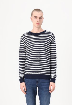 Marineblå og hvit stripet strikkegenser med ribbestrikket rund hals og mansjetter, med et teksturert design og lett stoff. Kombinert med denimjeans.