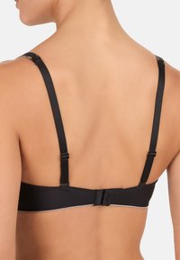 Soutien-gorge noir avec bretelles réglables, fermeture à crochet et œillet, tissu lisse, design sans coutures et une bordure contrastante le long de la bande.