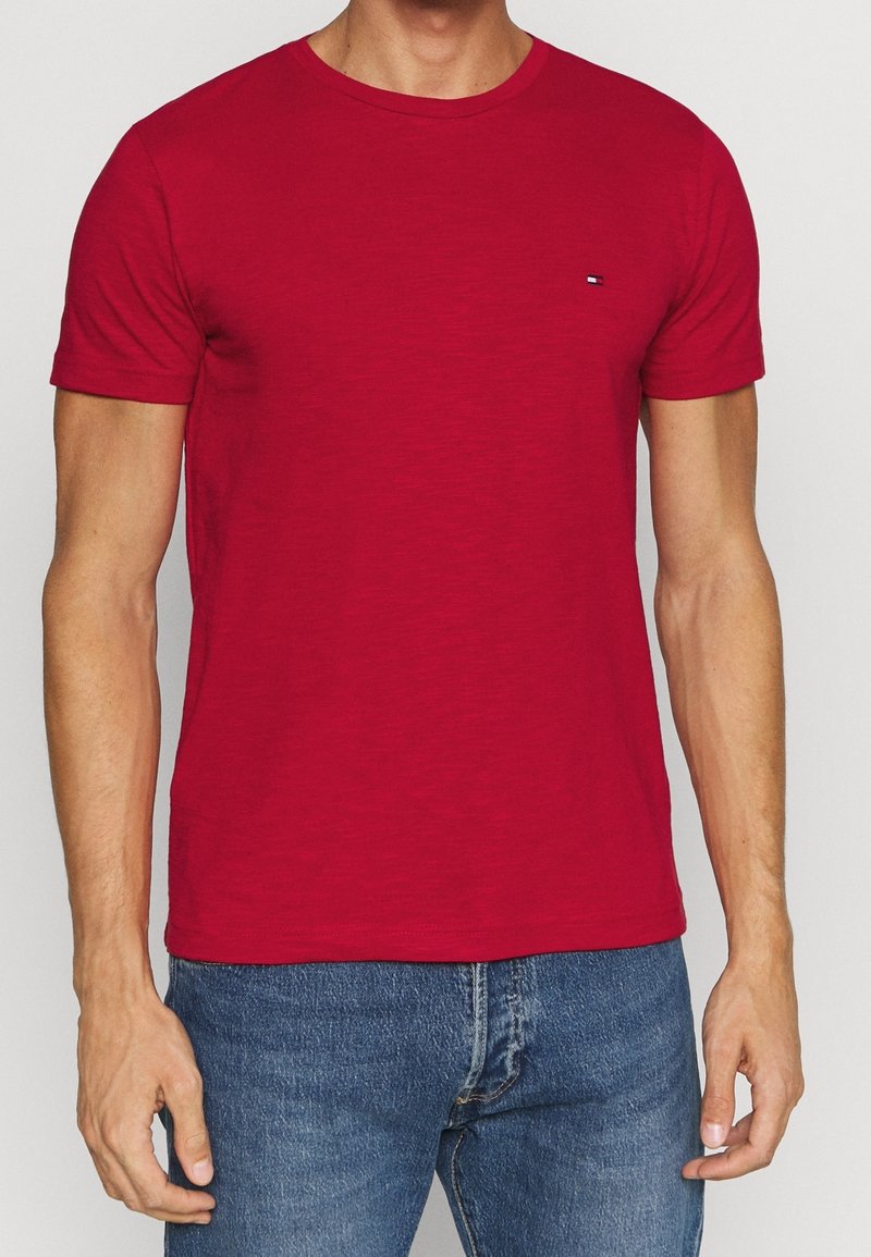 T-shirt in cotone rosso con collo rotondo e maniche corte. Presenta un piccolo emblema sulla parte sinistra del petto e una vestibilità comoda.