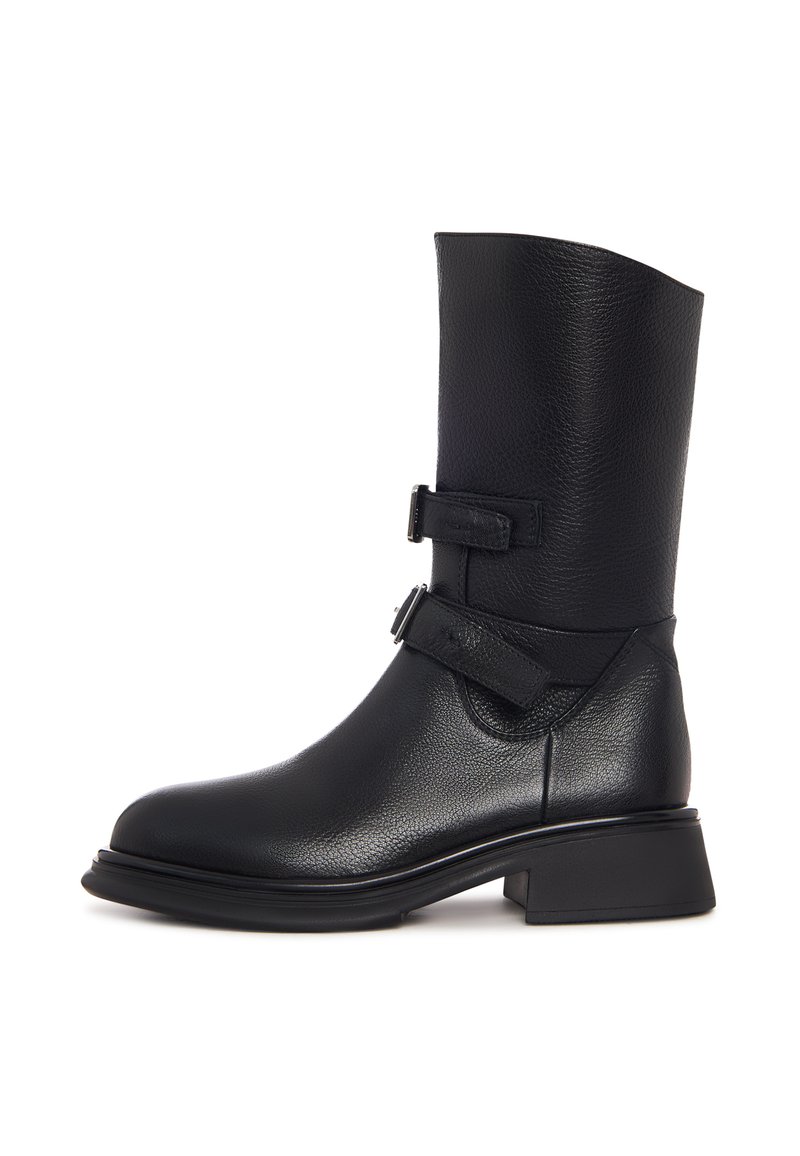 Botin de piele neagră, cu gleznă, având un șanț larg și structurat, două curele ajustabile, un vârf rotunjit și un toc modest tip bloc. Suprafață texturată.