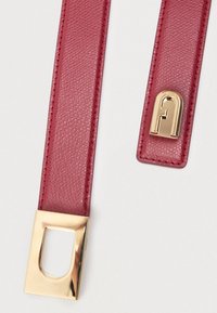 Sarkans teksturēts ādas josta ar zelta taisnstūra sprādzi un zelta akcentu. Abas malas ir kārtīgi noformētas.