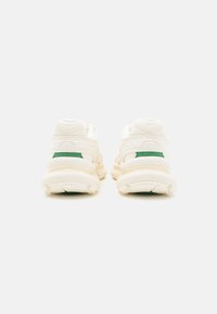 Baskets blanches avec un dessus texturé, présentant des accents verts sur le talon. Semelle épaisse et rembourrée conçue pour le confort et le soutien.