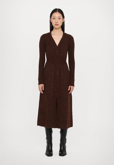 Braun gestricktes Kleid mit V-Ausschnitt, langen Ärmeln und einem Schlitz vorne. Besitzt kleine Knöpfe in der Mitte und eine figurbetonte Silhouette.